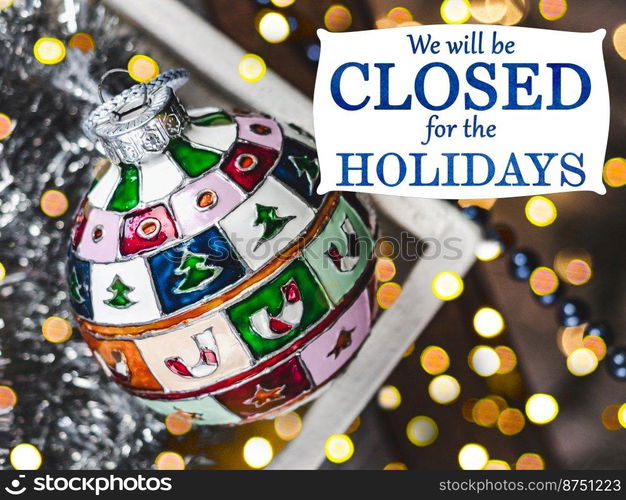 We will be closed for the Holidays. Beautiful signboard for Christmas and New Year holidays. Colorful Christmas balls on the background of the Christmas tree. Closeup, top view. Holidays concept. We will be closed for the Holidays