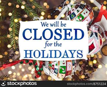 We will be closed for the Holidays. Beautiful signboard for Christmas and New Year holidays. Colorful Christmas balls on the background of the Christmas tree. Closeup, top view. Holidays concept. We will be closed for the Holidays