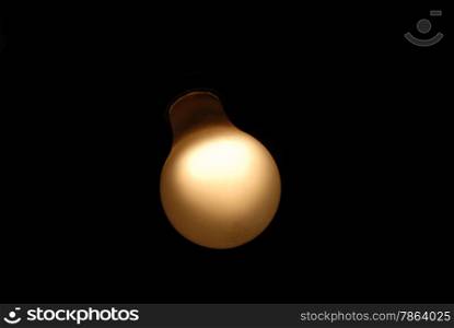 Weak yellow lightbulb glowing in darkness.