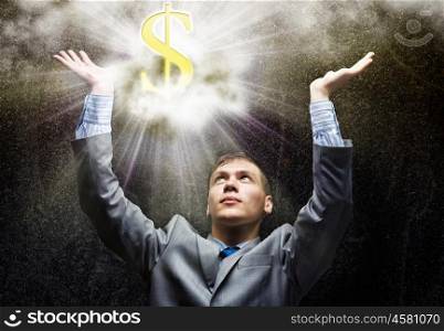 Wealth concept. Businessman praying at dollar sign above