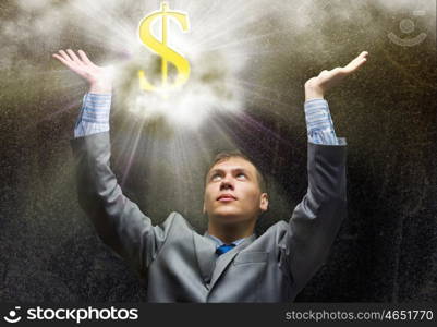Wealth concept. Businessman praying at dollar sign above