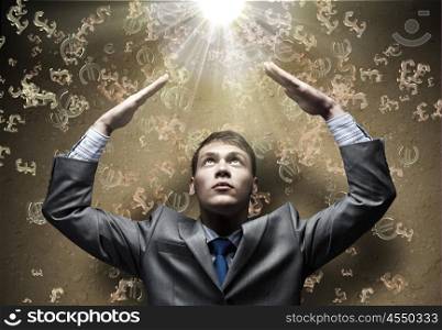 Wealth concept. Businessman protecting head with arms from falling currency signs