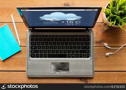 weather cast, business and technology concept - close up of laptop computer with forecast on screen on wooden table