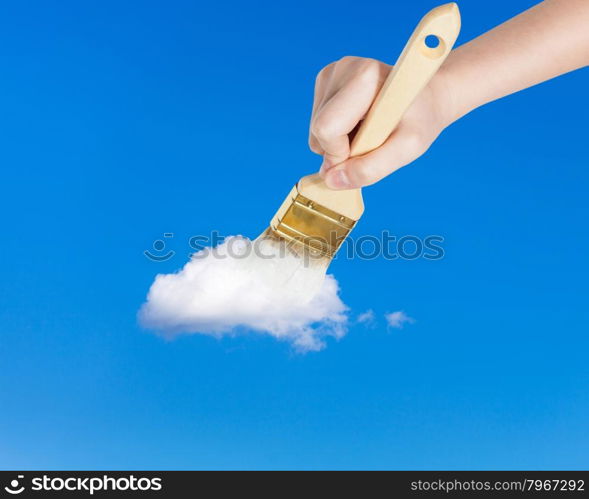 weather concept - hand with paintbrush paints lonely white little cloud in the summer blue sky