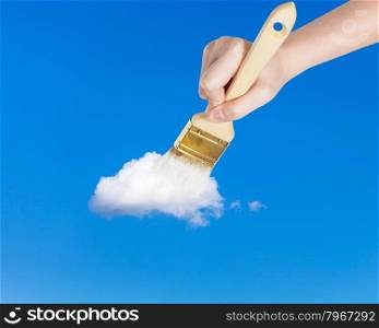 weather concept - hand with paintbrush paints lonely white little cloud in the summer blue sky
