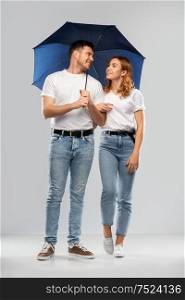 weather, relationships and protection concept - portrait of happy couple in white t-shirts with umbrella over grey background. happy couple in white t-shirts with umbrella