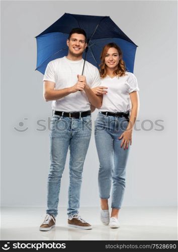 weather, relationships and protection concept - portrait of happy couple in white t-shirts with umbrella over grey background. happy couple in white t-shirts with umbrella