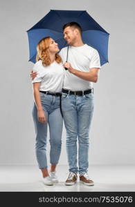 weather, relationships and protection concept - portrait of happy couple in white t-shirts with umbrella over grey background. happy couple in white t-shirts with umbrella