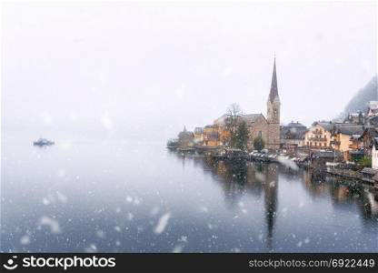 Weather theme image with a dense snowfall falling over the HallstAtter See and the Hallstatt village, one of the UNESCO Heritage Sites in Austria, in November.