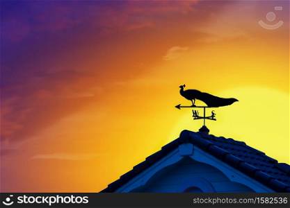 weather vane at sunrise with bright colors in clouds for early morning wake up.