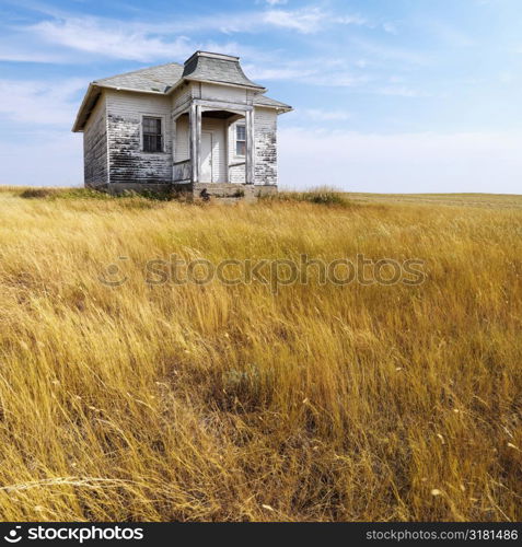 Weathered abandoned building in remote grassland.