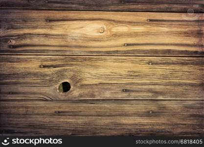 weathered grained wood of old barn wall with nails, staple and knothole