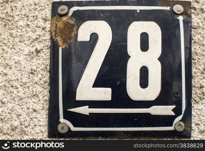 Weathered grunge square metal enameled plate of number of street address with number 28 closeup