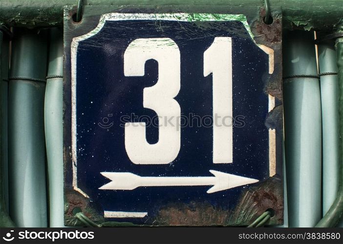 Weathered grunge square metal enameled plate of number of street address with number 31 closeup