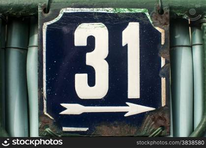 Weathered grunge square metal enameled plate of number of street address with number 31 closeup