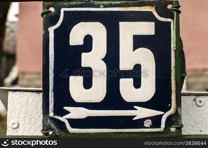 Weathered grunge square metal enameled plate of number of street address with number 35 closeup