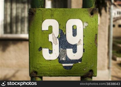 Weathered grunge square metal enameled plate of number of street address with number 39 closeup
