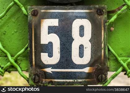 Weathered grunge square metal enameled plate of number of street address with number 58 closeup