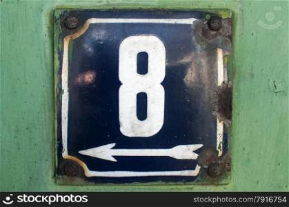 Weathered grunge square metal enameled plate of number of street address with number 8 closeup