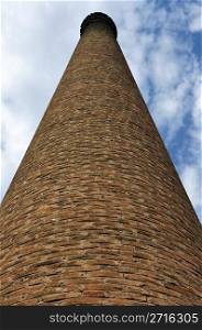 Weathered industrial brick chimney of an abandoned factory.