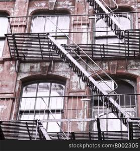 Weathered red building with fire escape stairs in New York City, USA