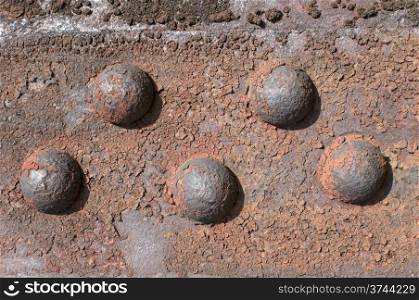 Weathered rusty iron element with centennial rivets link as background