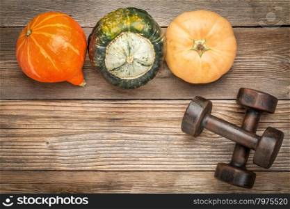 weathered wood background with a couple of vintage dumbbells and winter squash
