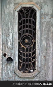 Weathered wooden door with peeling paint and vintage metalwork pattern.