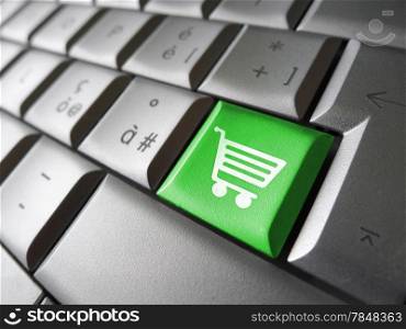Web and Internet on line shopping concept with basket icon and symbol on a green laptop computer key for website and online business.