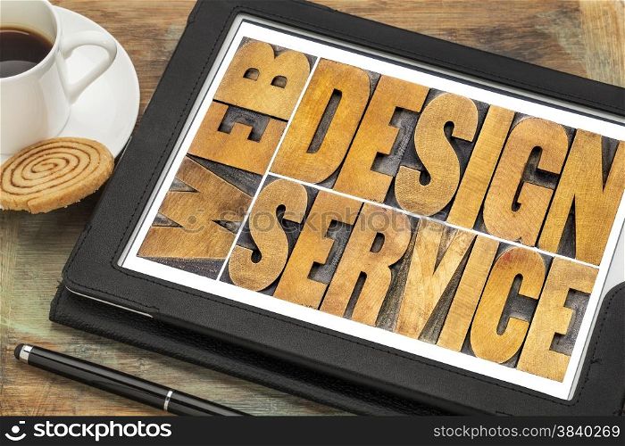 web design service word abstract - isolated text in letterpress wood type on a digital tablet with a cup of coffee