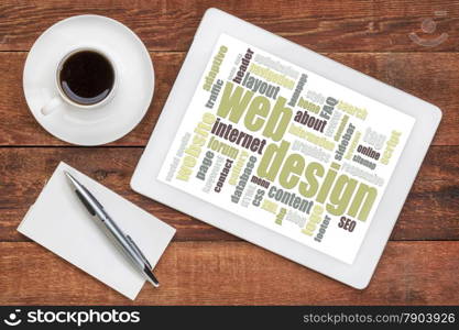 web design word cloud on a digital tablet with a cup of coffee on a rustic wooden table