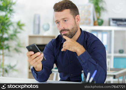 web developer working at his desk and checking his phone