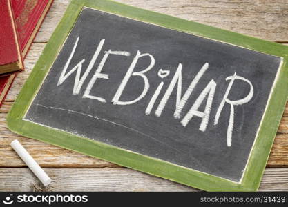 webinar word in white chalk handwriting on a vintage slate blackboard with books