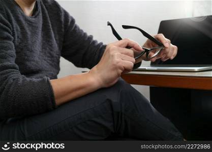Website designer holding eyeglass working computer laptop,digital tablet on wood table