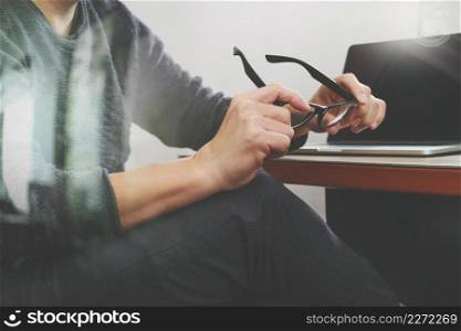 Website designer holding eyeglass working computer laptop on wood table,filter effect 
