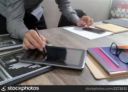 Website designer holding smart phone and working computer digital tablet on wood table 