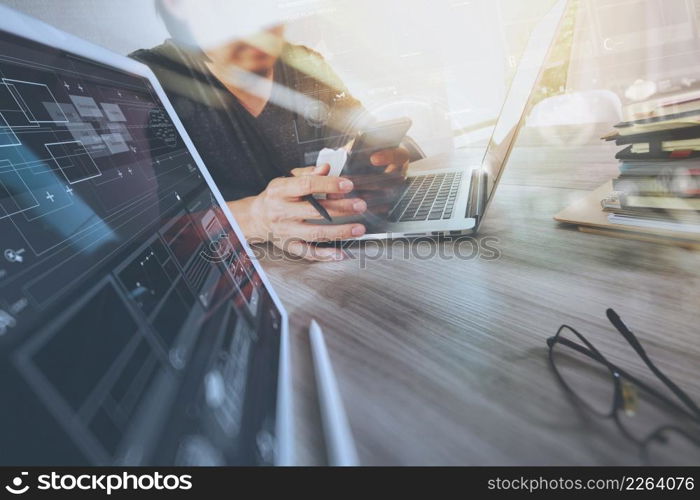 Website designer working digital tablet and computer laptop with smart phone and digital design diagram and stack of books on wooden desk as concept