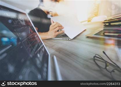 Website designer working digital tablet and computer laptop with smart phone and digital design diagram and stack of books on wooden desk as concept