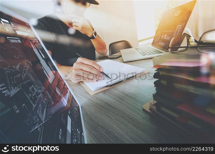 Website designer working digital tablet and computer laptop with smart phone and digital design diagram and stack of books on wooden desk as concept