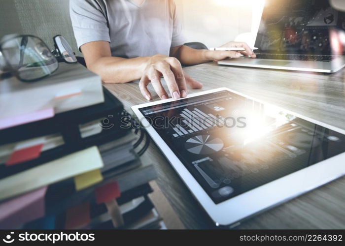 Website designer working digital tablet and computer laptop with smart phone and digital design diagram and stack of books on wooden desk as concept