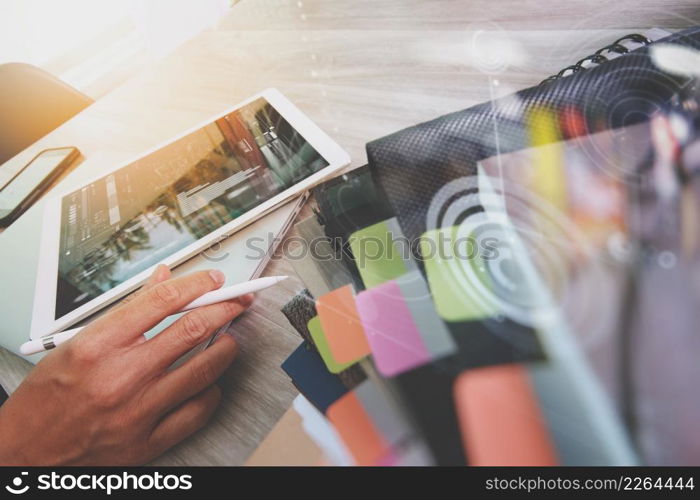 Website designer working digital tablet and computer laptop with smart phone and digital design diagram and stack of books on wooden desk as concept