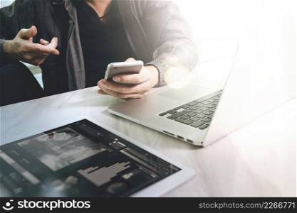 Website designer working digital tablet and computer laptop  with smart phone and graphics design diagram on marble desk as concept