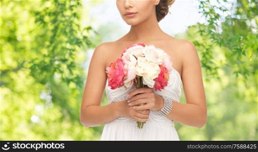 wedding and people concept - beautiful young woman or bride with bouquet of flowers over green natural background. young woman or bride with bouquet of flowers