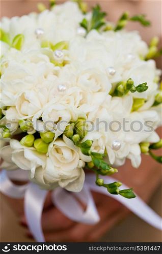 Wedding bouquet from white freesias closeup in bride&rsquo;s hands