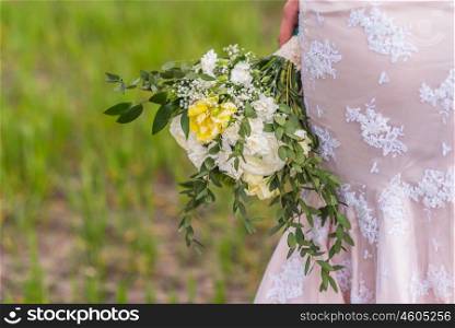 wedding bouquet in hands of the bride on background of the dress