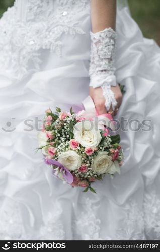 wedding bouquet in hands of the bride with roses, orchids and ribbons