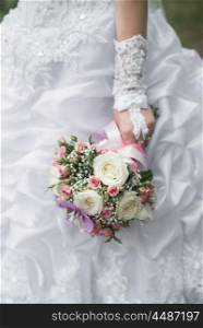 wedding bouquet in hands of the bride with roses, orchids and ribbons