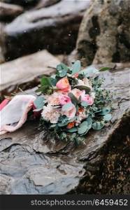 wedding bouquet of peonies with ribbons on stone, close-up, it&rsquo;s snowing