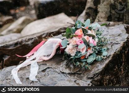 wedding bouquet of peonies with ribbons on stone, close-up, it&rsquo;s snowing
