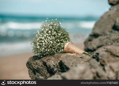 wedding bouquet of white flowers on stones on the background of the sea